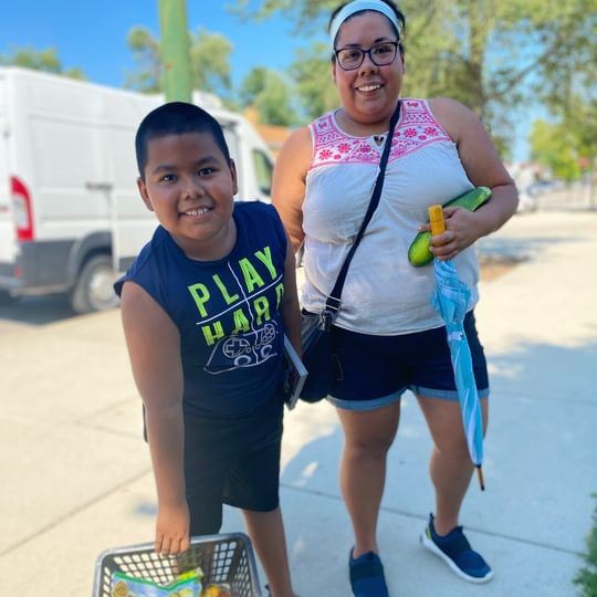 A mother and her son pickup fresh groceries at a community pickup day