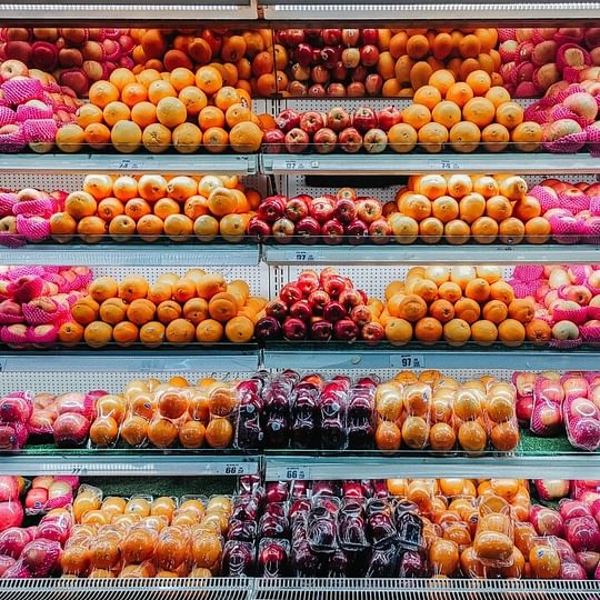 Rows of fresh fruits in vibrant oranges and reds: apples, oranges, peaches, plums...