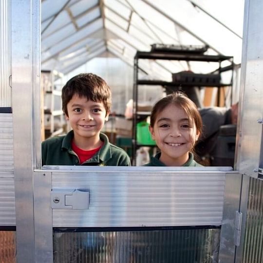 Students smile inside a greenhouse