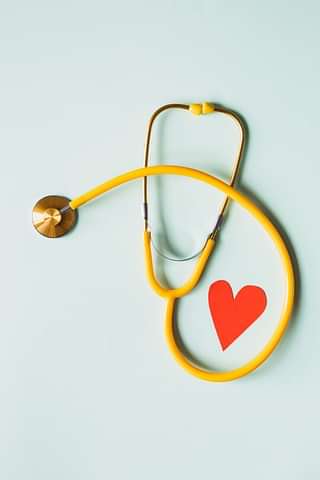 A yellow stethescope, accompanied by a red paper heart